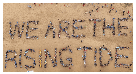 the words "we are the rising tide" spelt out in people, photo taken from the air